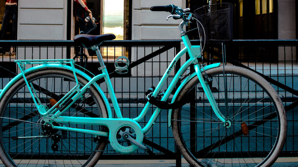 Un vélo de ville attaché à une barrière avec un antivol.